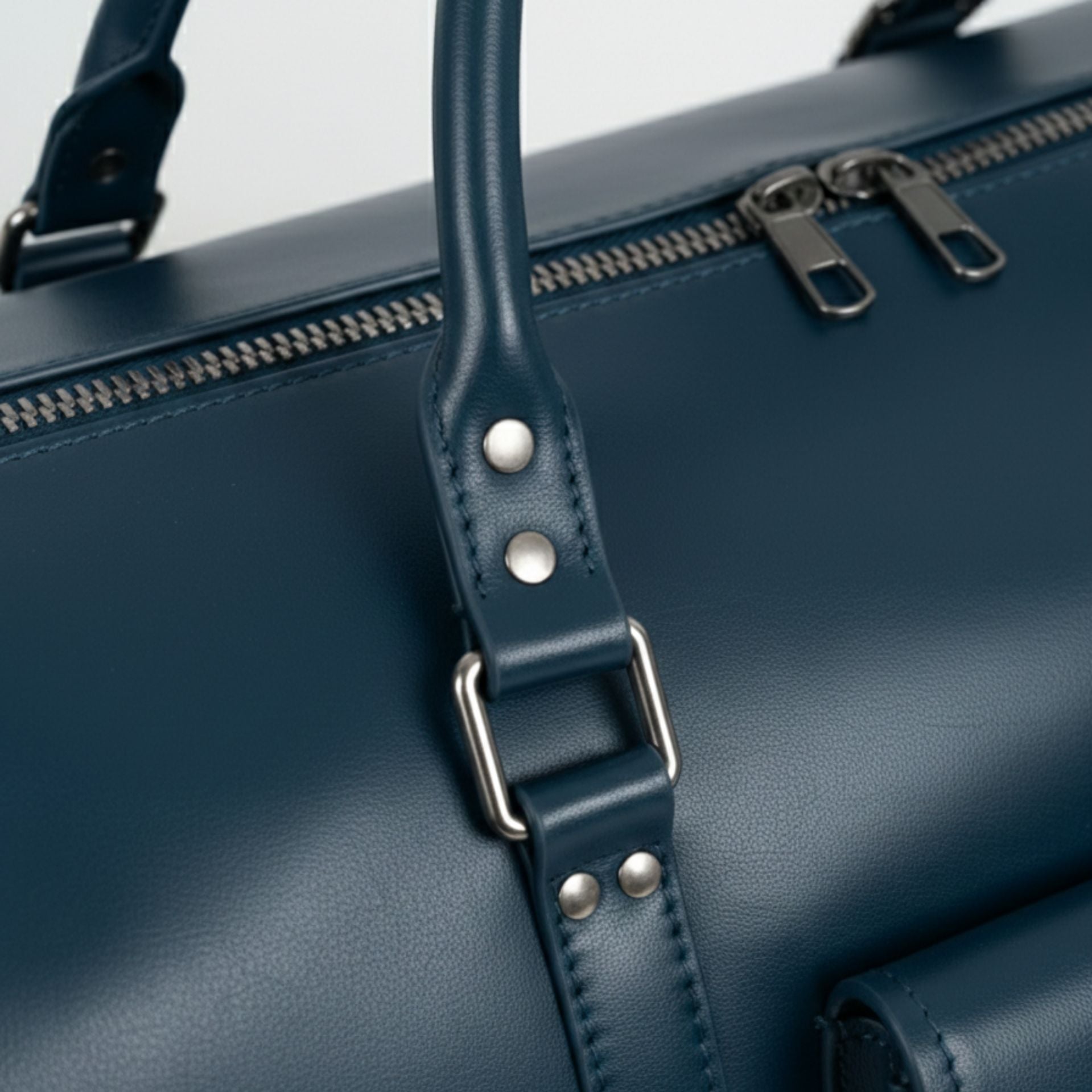 close up of navy leather duffle bag handle stitching and metal hardware.