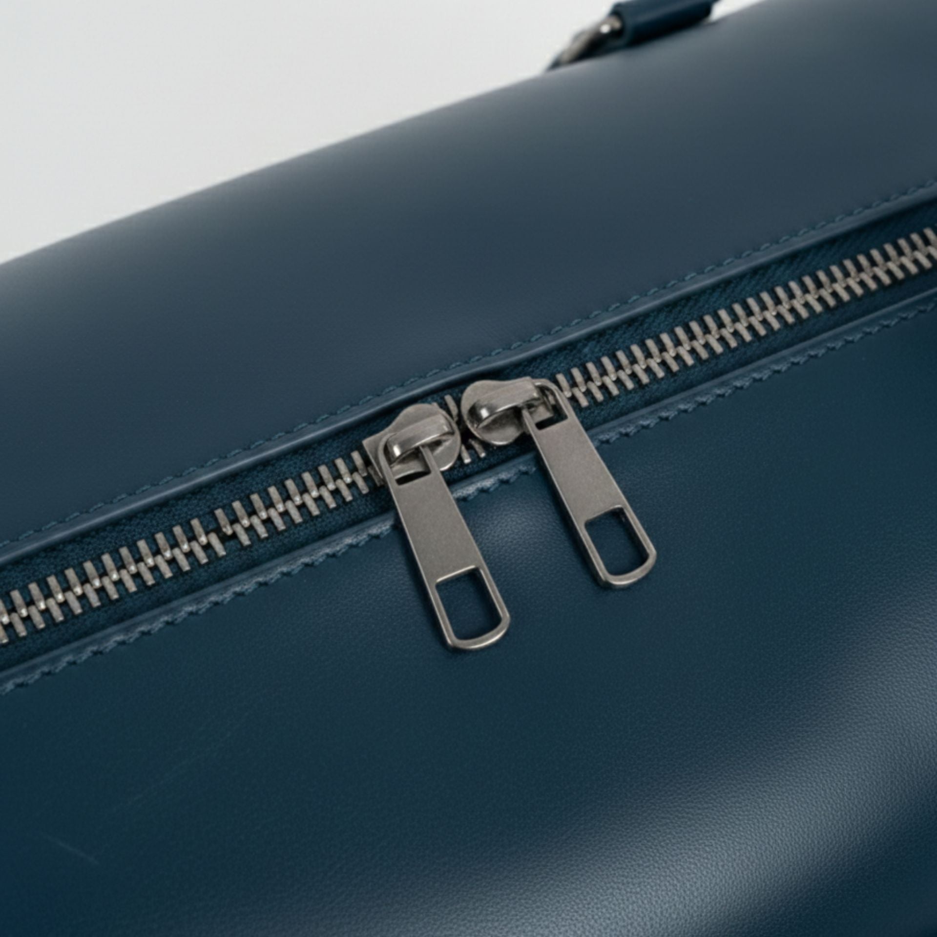 close up of double metal zipper on navy genuine leather travel bag.