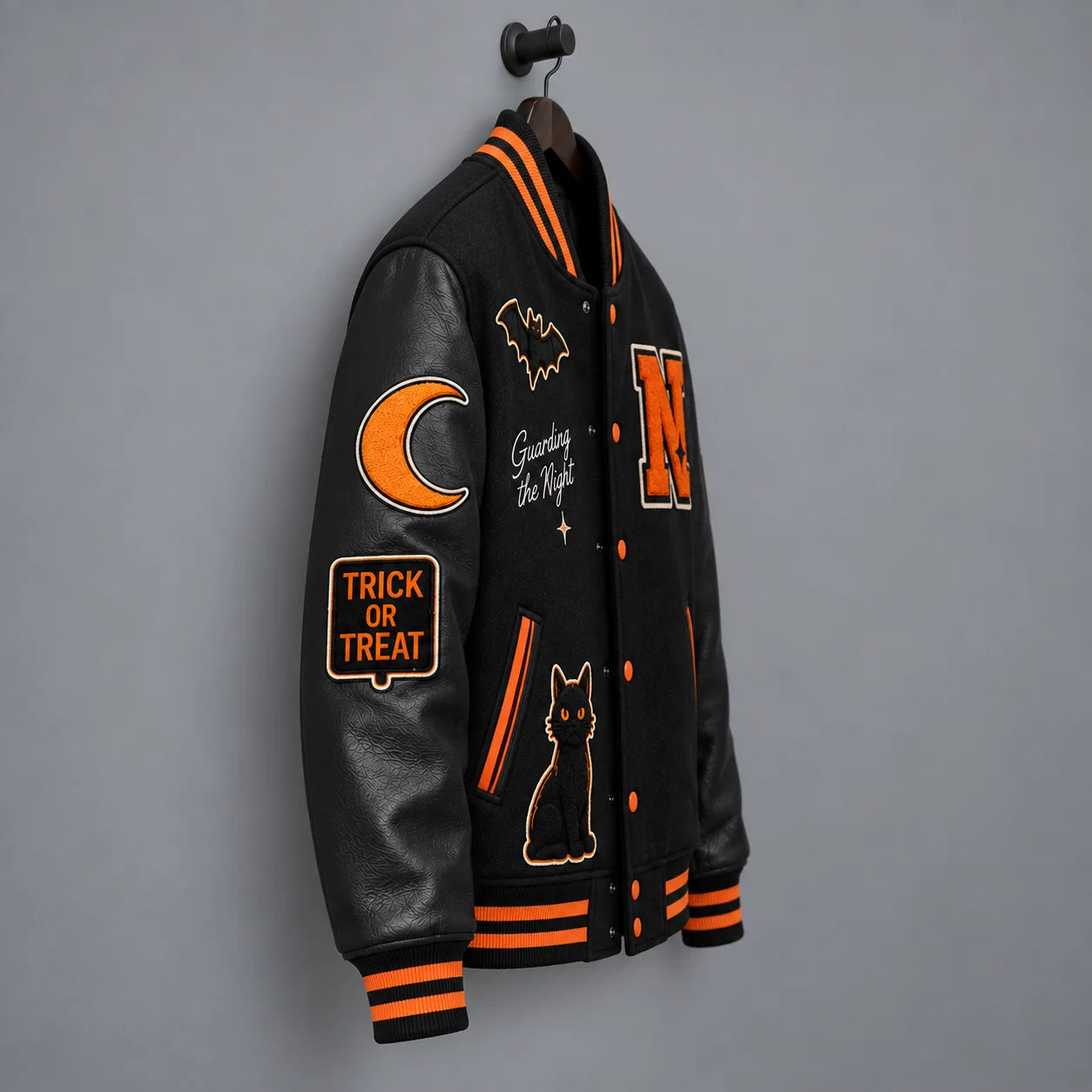 Side-angle hanging view of black Halloween varsity jacket highlighting leather sleeve, moon and Trick or Treat patches
