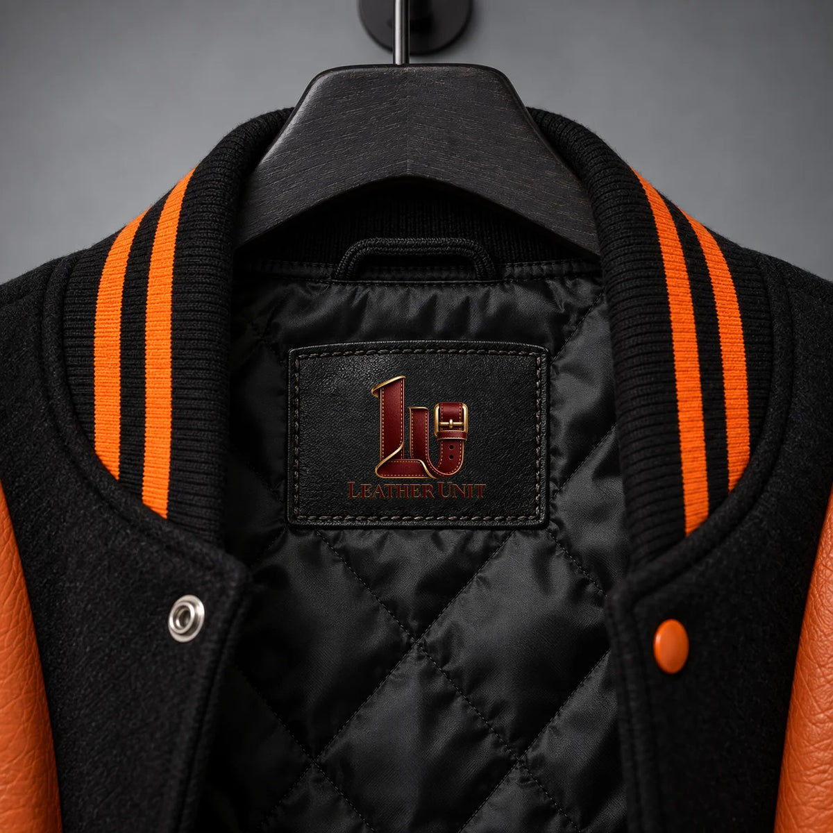 Collar close-up of Nightborn jacket showing black quilted lining, embroidered label and orange-black rib-knit trim