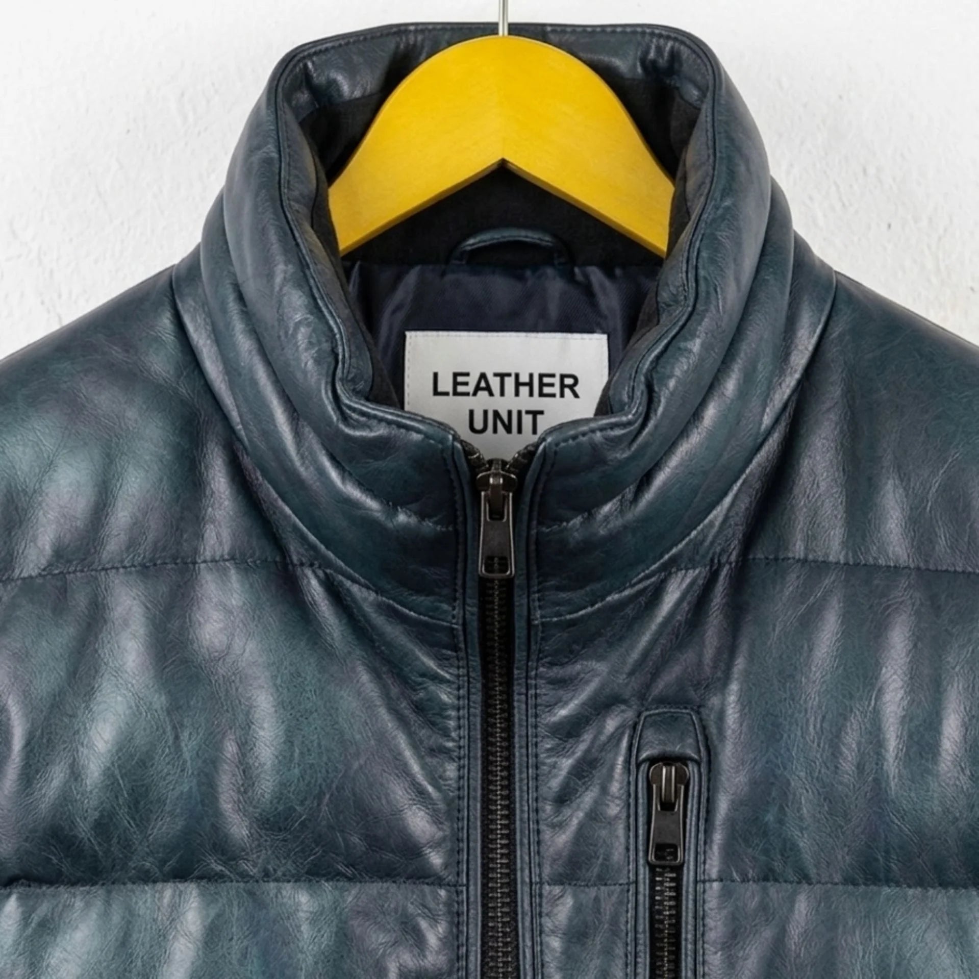 Close-up of collar and Leather Unit tag on teal leather puffer bomber jacket