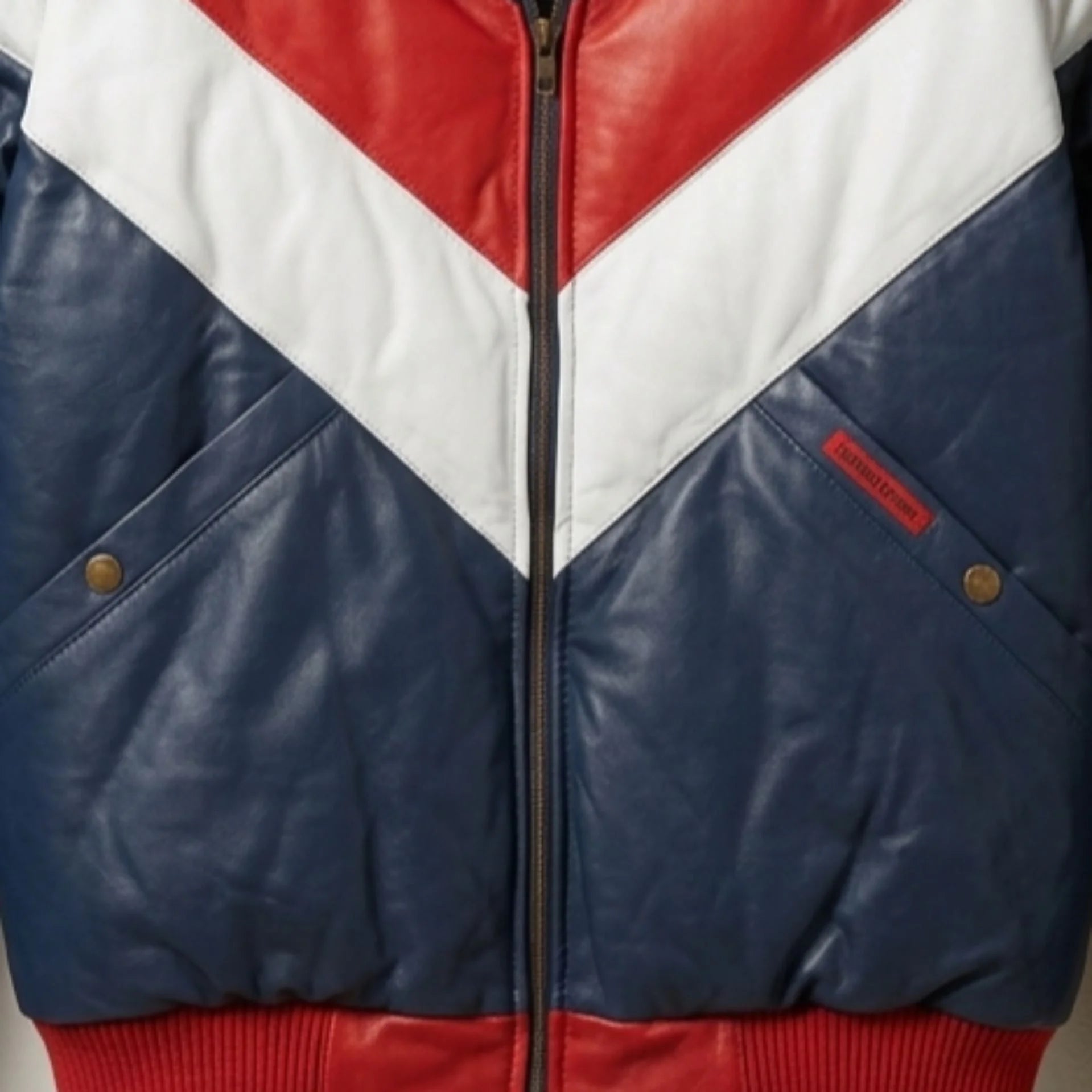 Close-up of functional pockets and heavy-duty zipper on two-tone leather puffer jacket