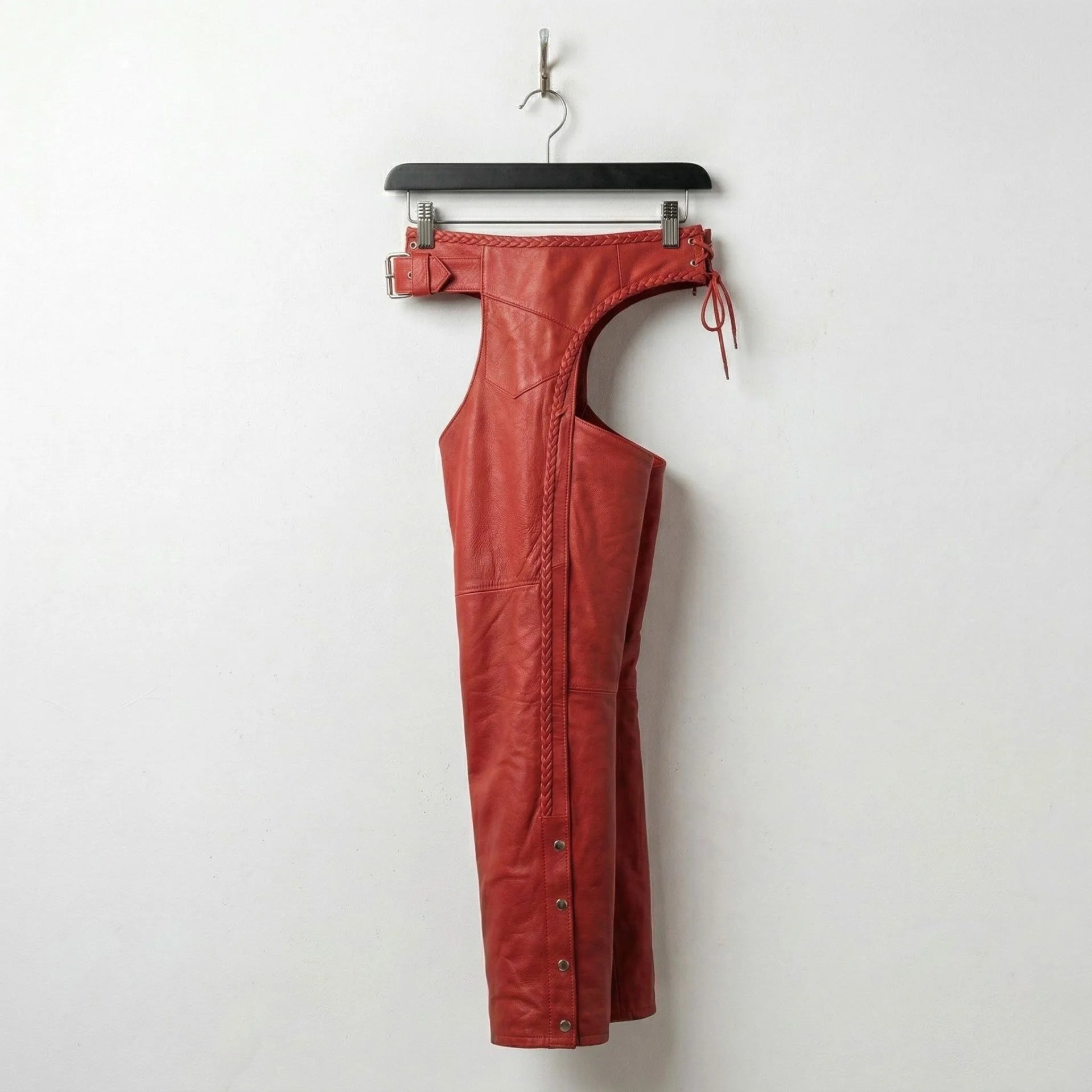 Opposite side view of red leather biker chaps hanging on hanger