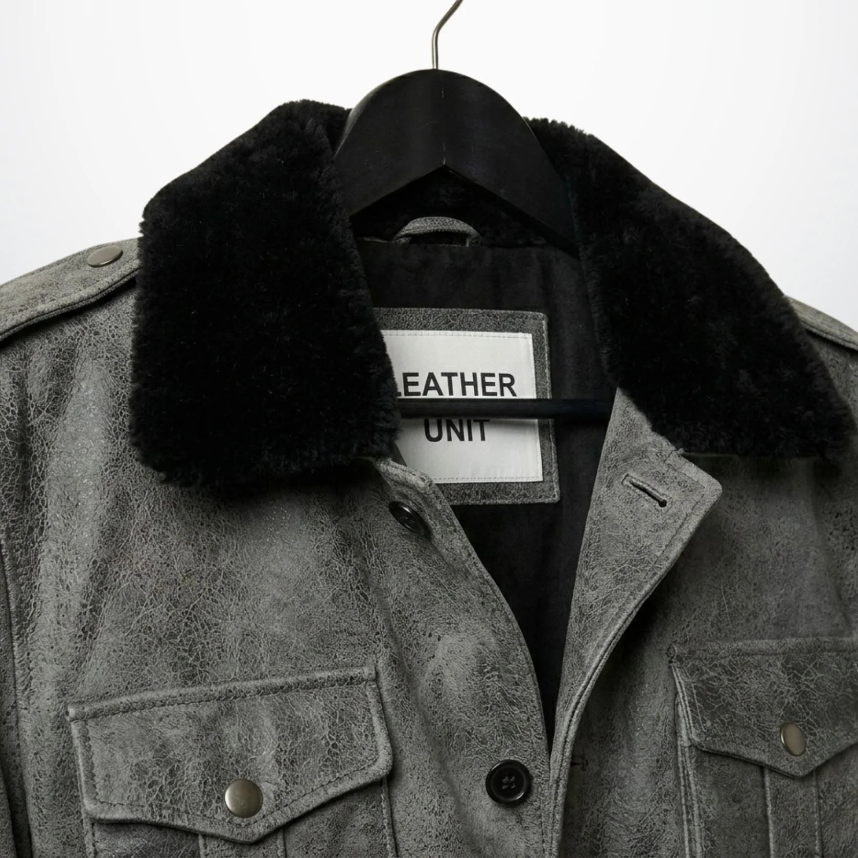 close up black shearling collar and epaulettes on mens grey leather coat.