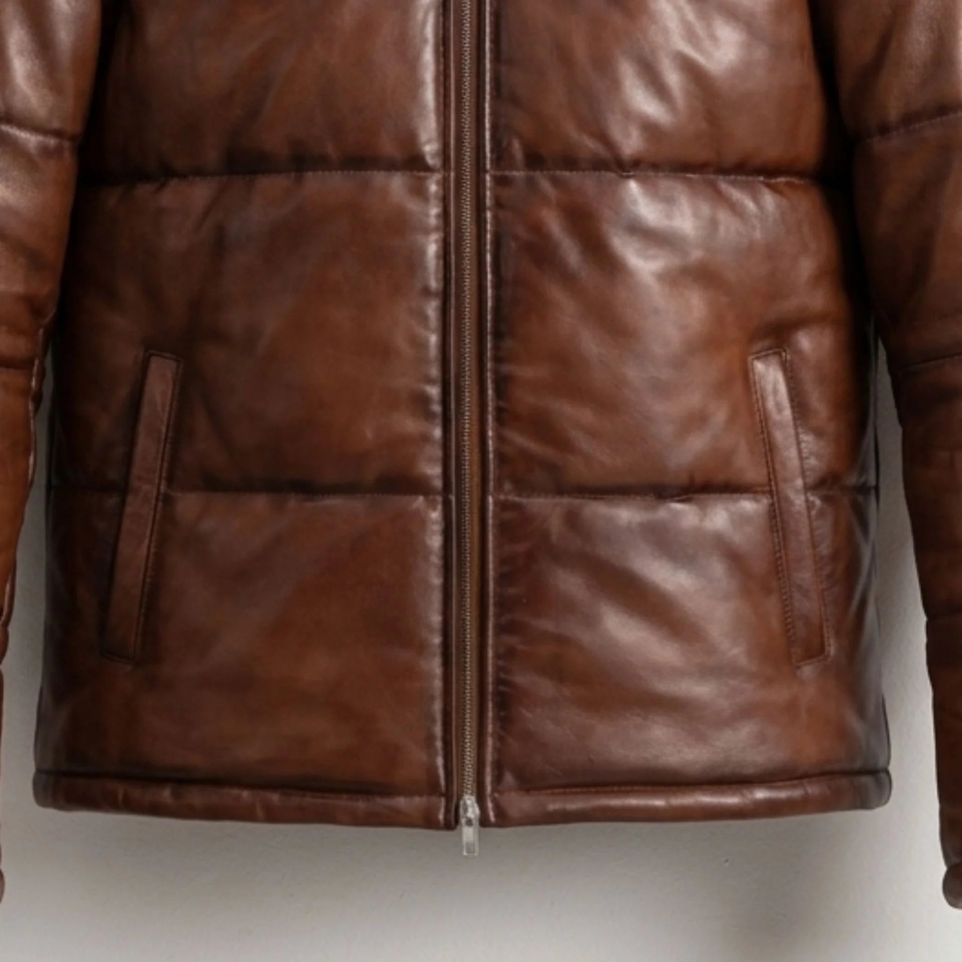 Close-up of front pockets and heavy-duty zipper on waxed brown leather puffer jacket