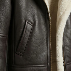 Close up of front pocket and zipper on women’s brown shearling leather bomber jacket