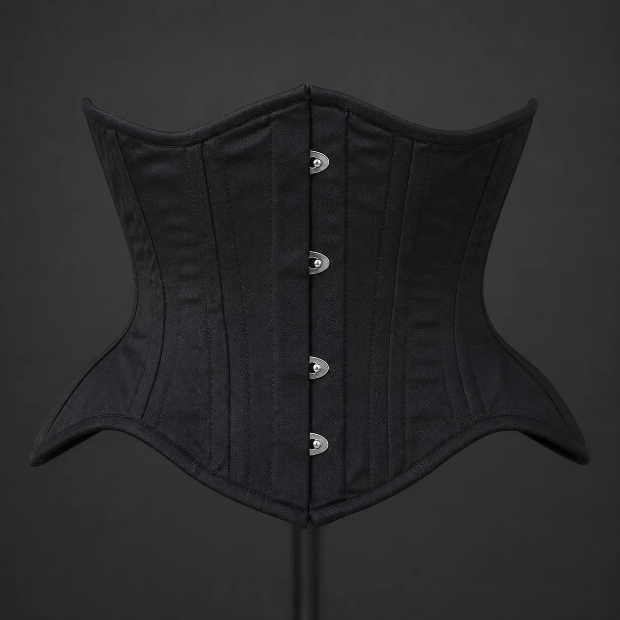 Front product view of black cotton underbust corset showing vertical boning channels and silver-tone busk fasteners