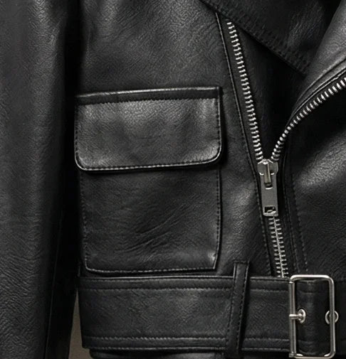 Close-up of front flap pocket and belt detail on black cropped leather jacket