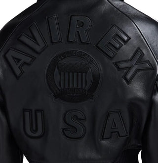 Close-up back view of black cropped leather bomber showing tonal oversized lettering, central crest and USA appliqué