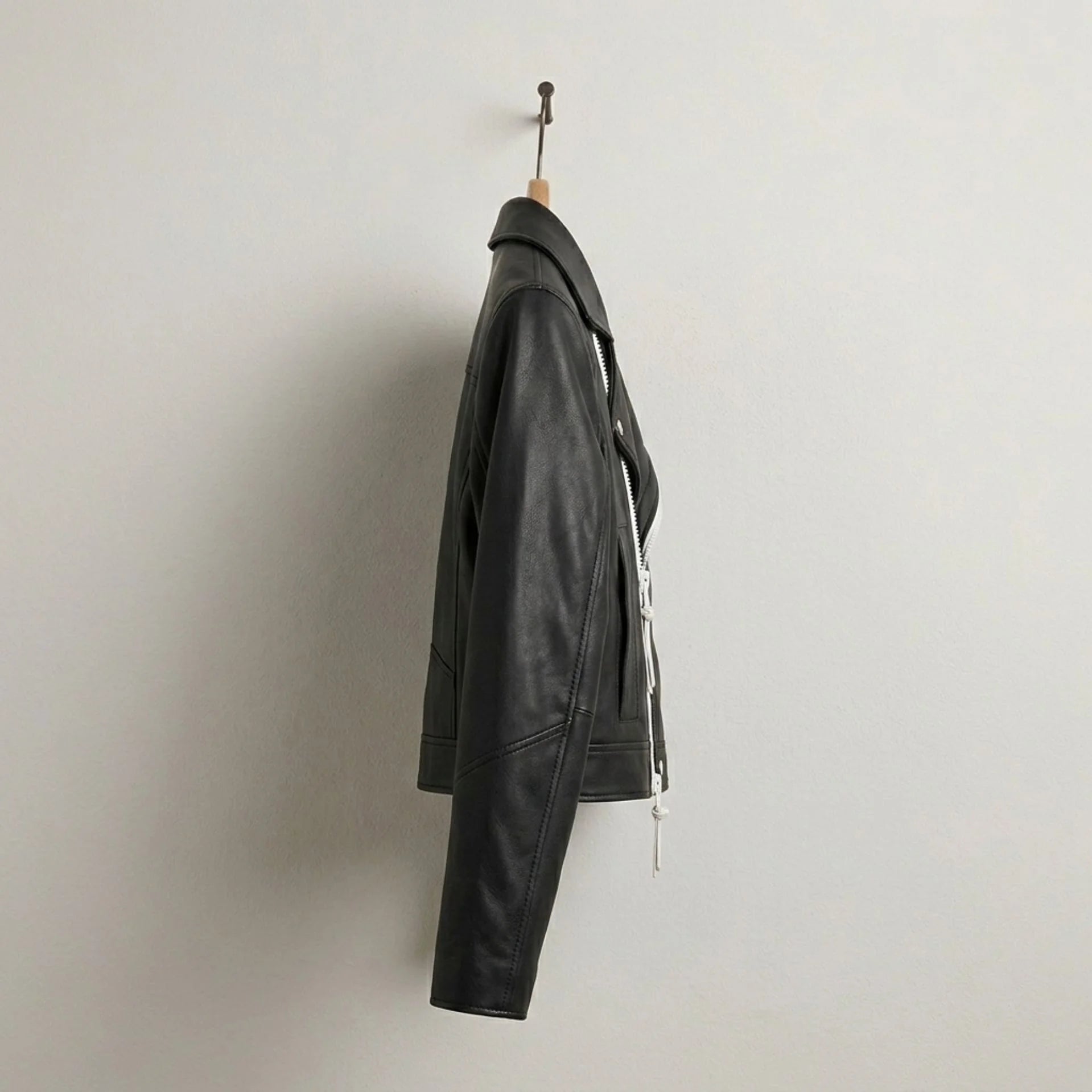 Side profile of women’s black moto leather jacket with asymmetrical zip