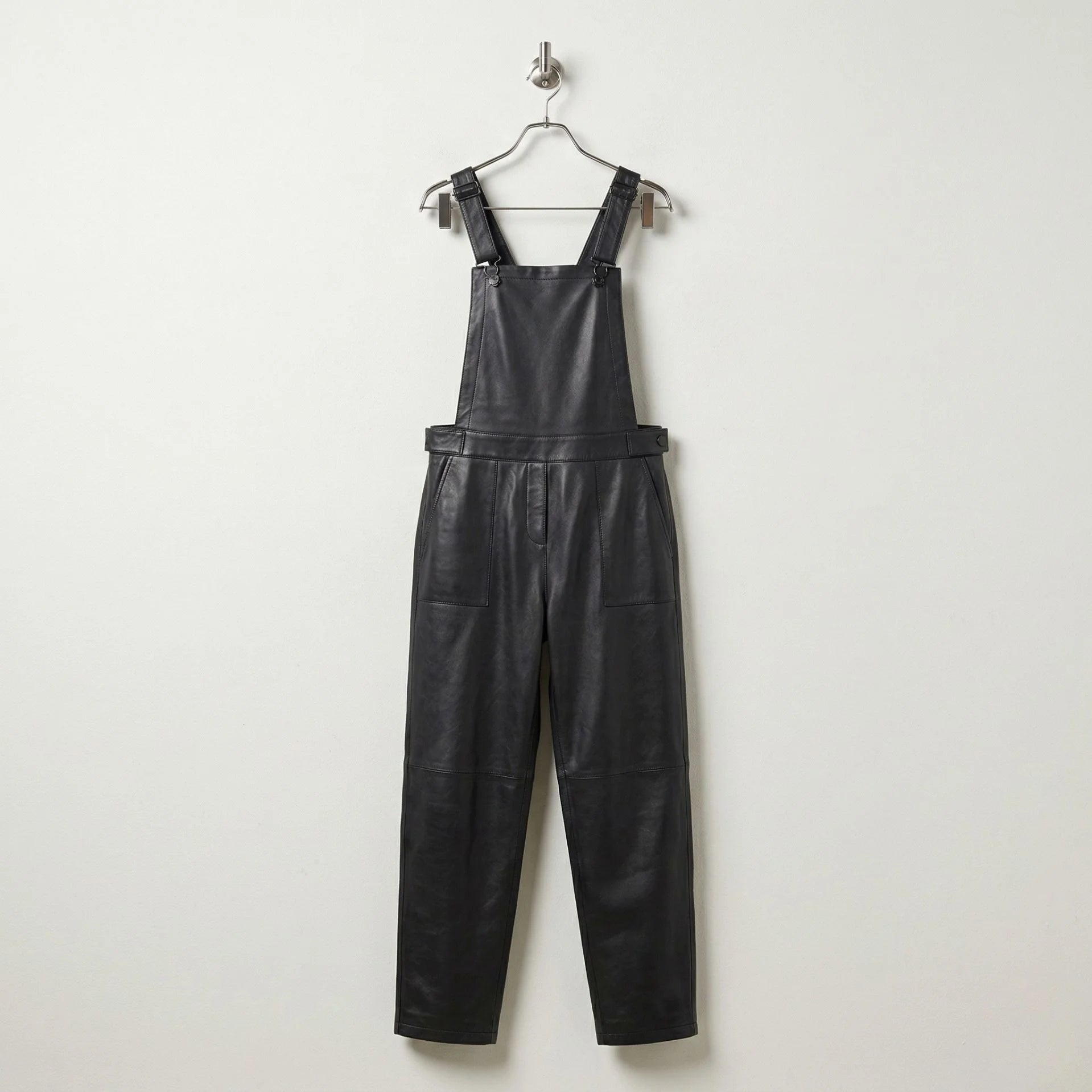 Front view of women’s black leather overalls with bib and tapered legs