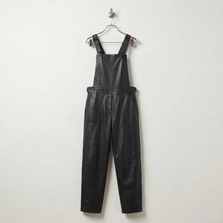 Front view of women’s black leather overalls with bib and tapered legs