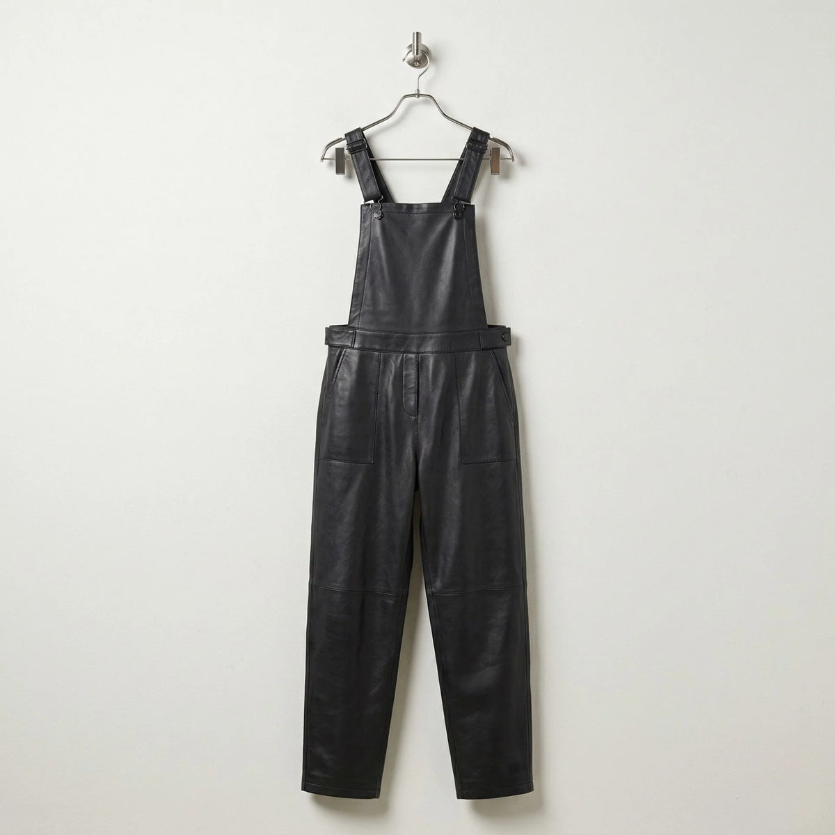 Front view of women’s black leather overalls with bib and tapered legs
