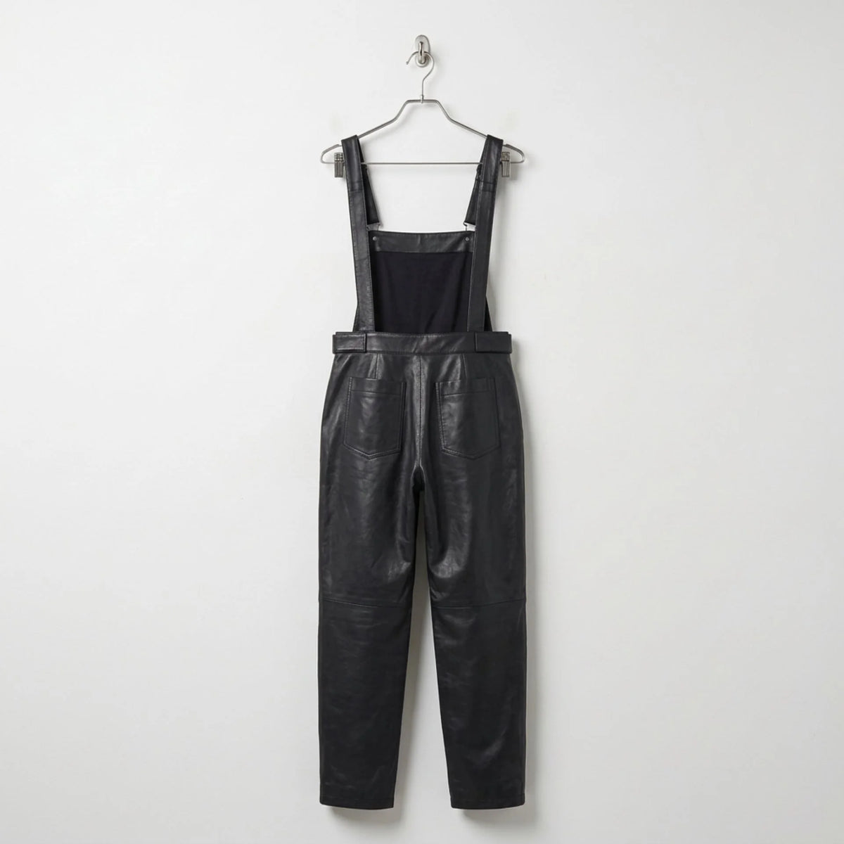 Back view of women’s black leather overalls showing rear pockets