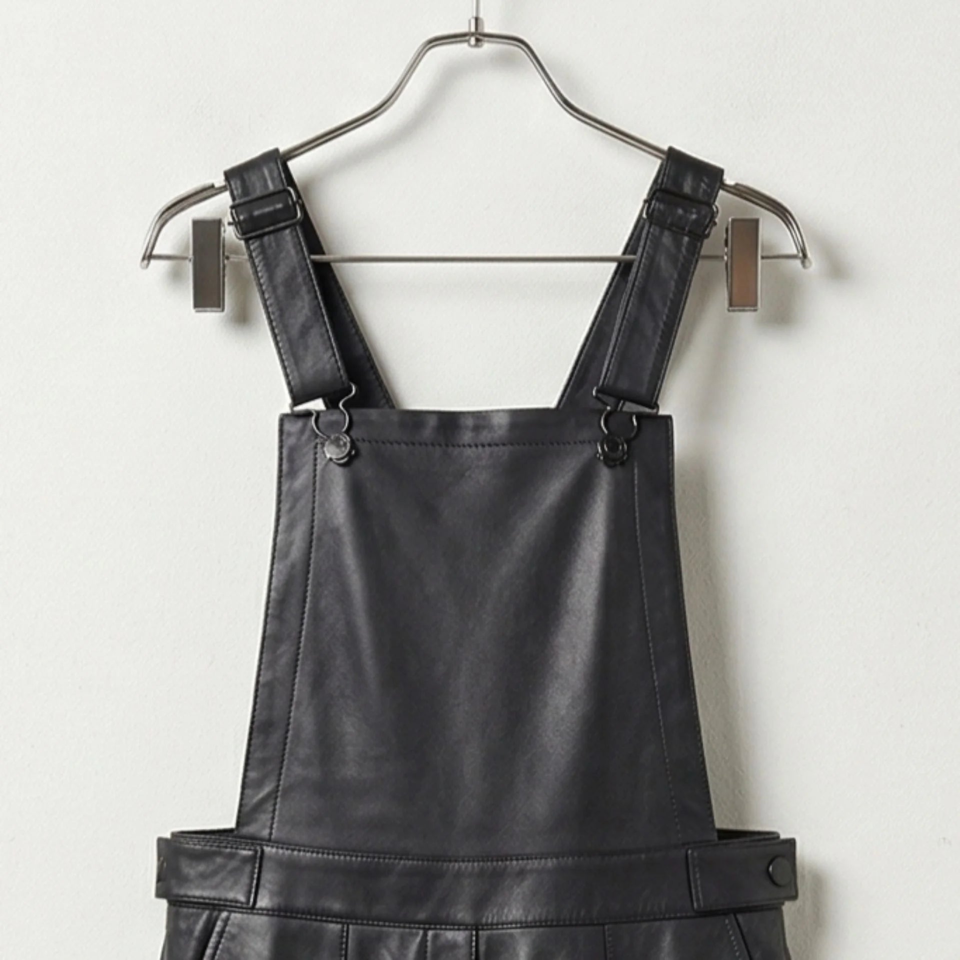 Close up of adjustable shoulder straps and bib on black leather overalls