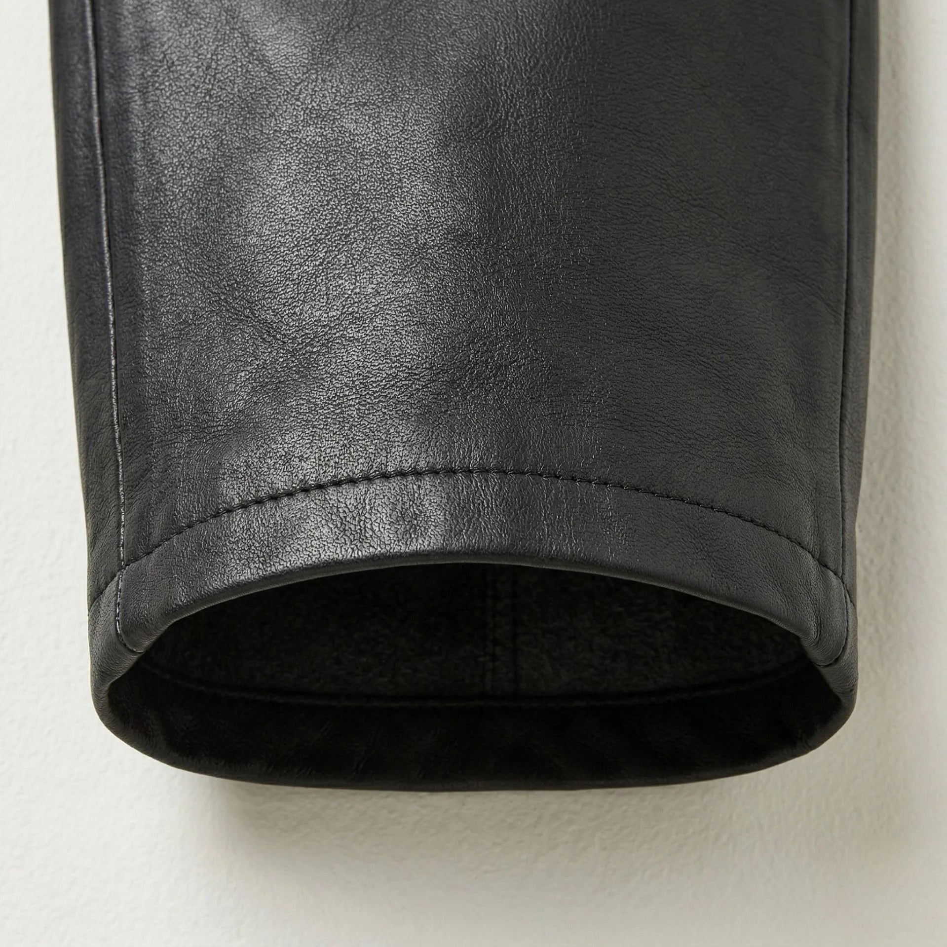 Close up of tapered leg hem on women’s black leather overalls