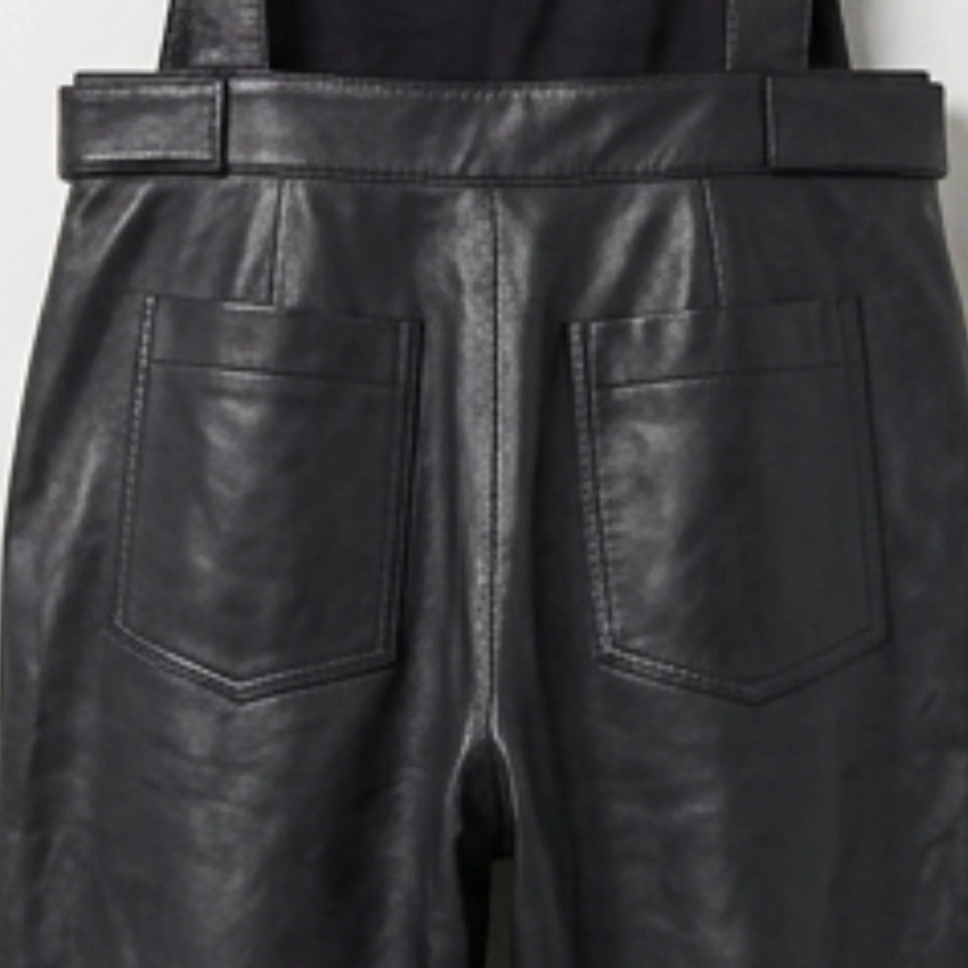 Close up of back patch pockets on black leather overalls