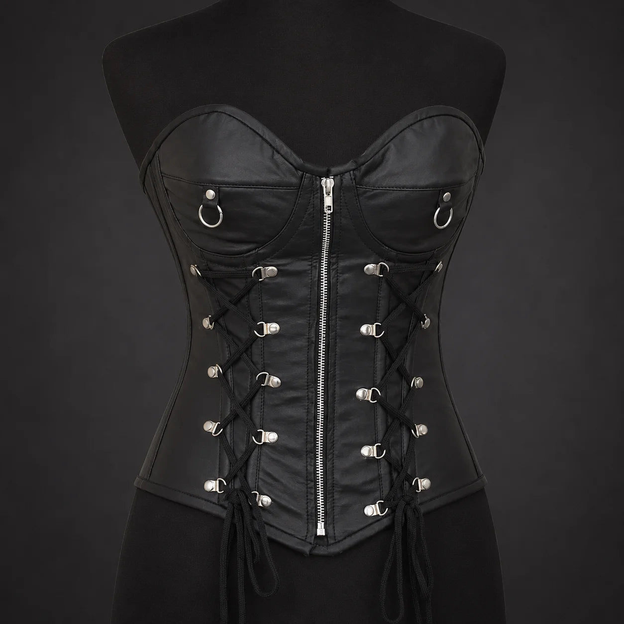 Front product view of women’s black leather corset with sweetheart bust, centre zipper, ring accents and side lace detail