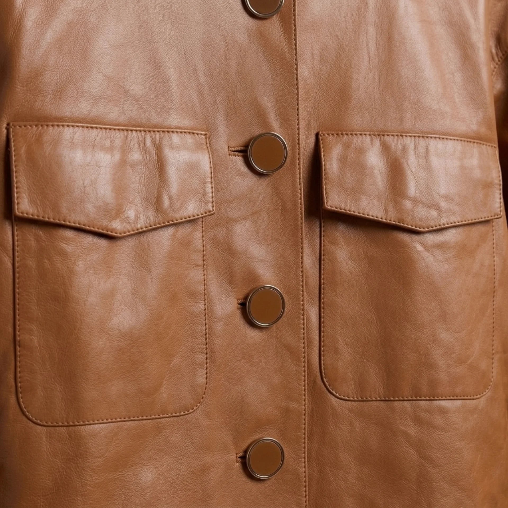 Close-up of chest flap pockets and button front on women’s collarless leather jacket