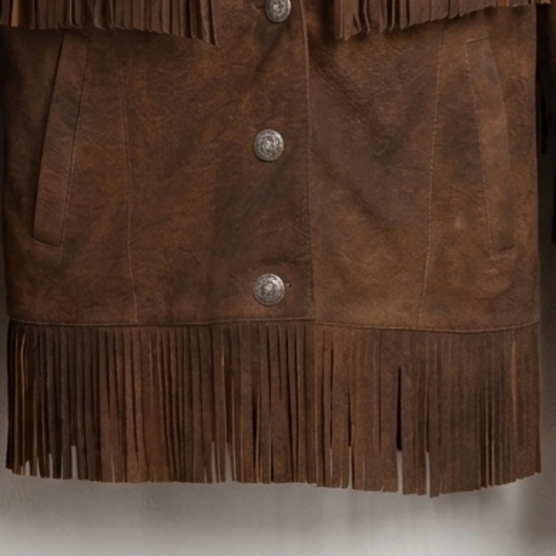 Close-up of button front and hem fringe on women’s brown leather fringe jacket