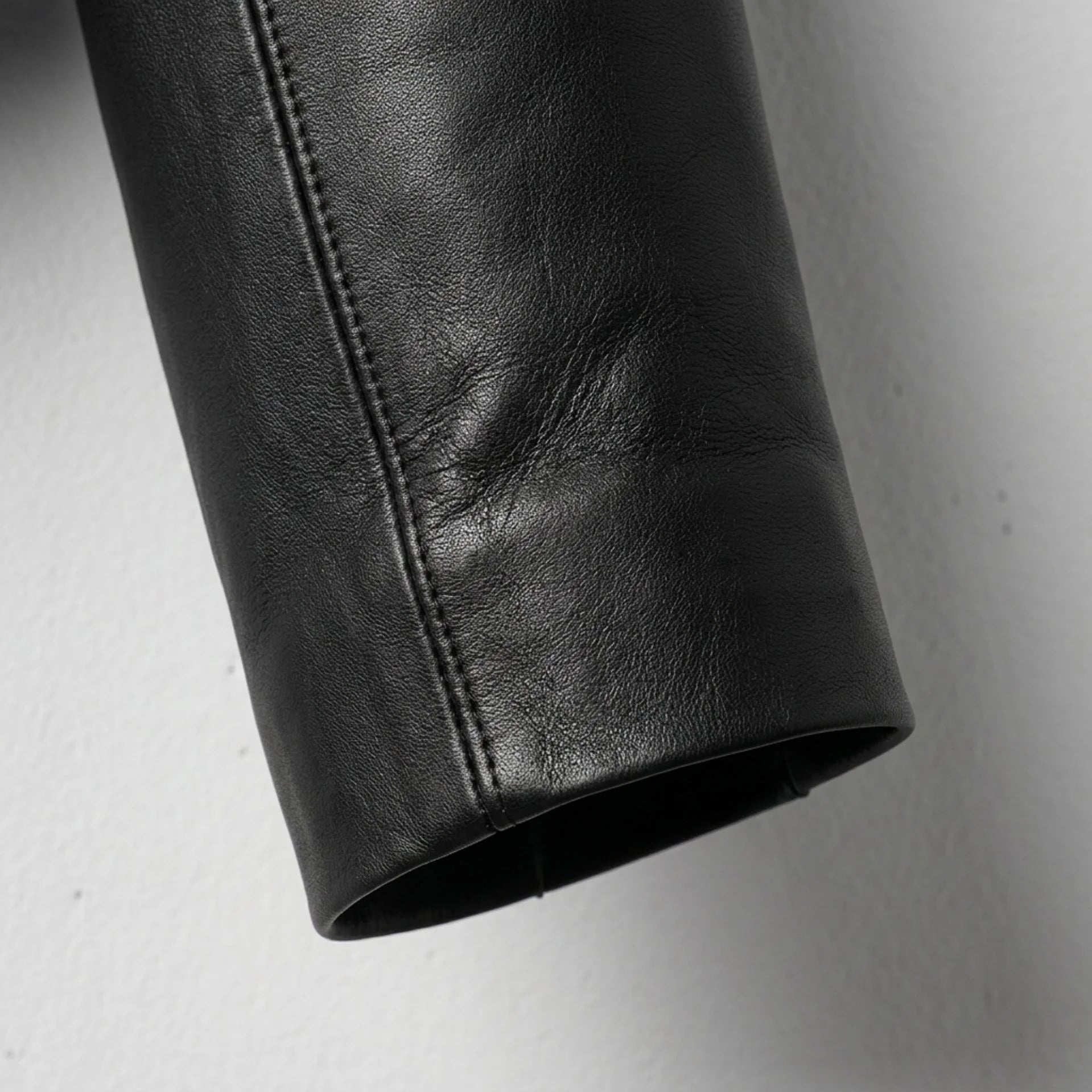 Detail of sleeve and stitching on women's cropped black leather jacket