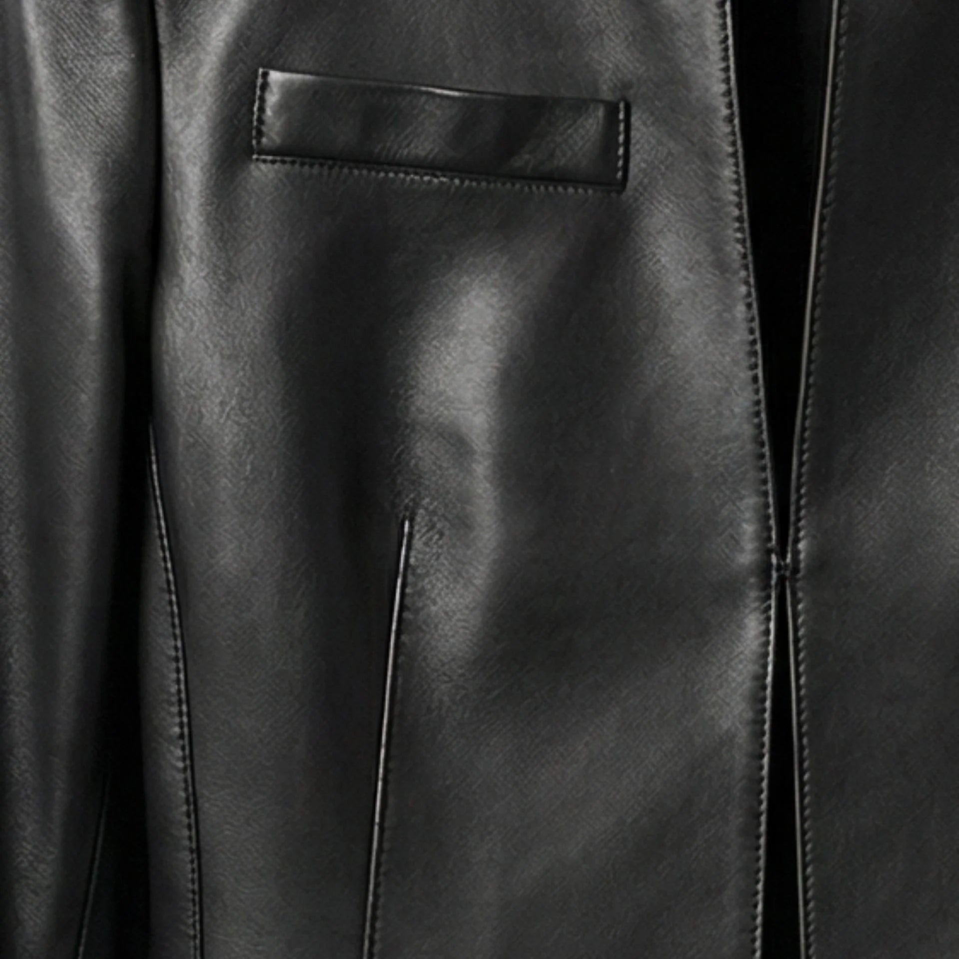 Close-up of chest welt pocket and front opening on women's black leather crop jacket