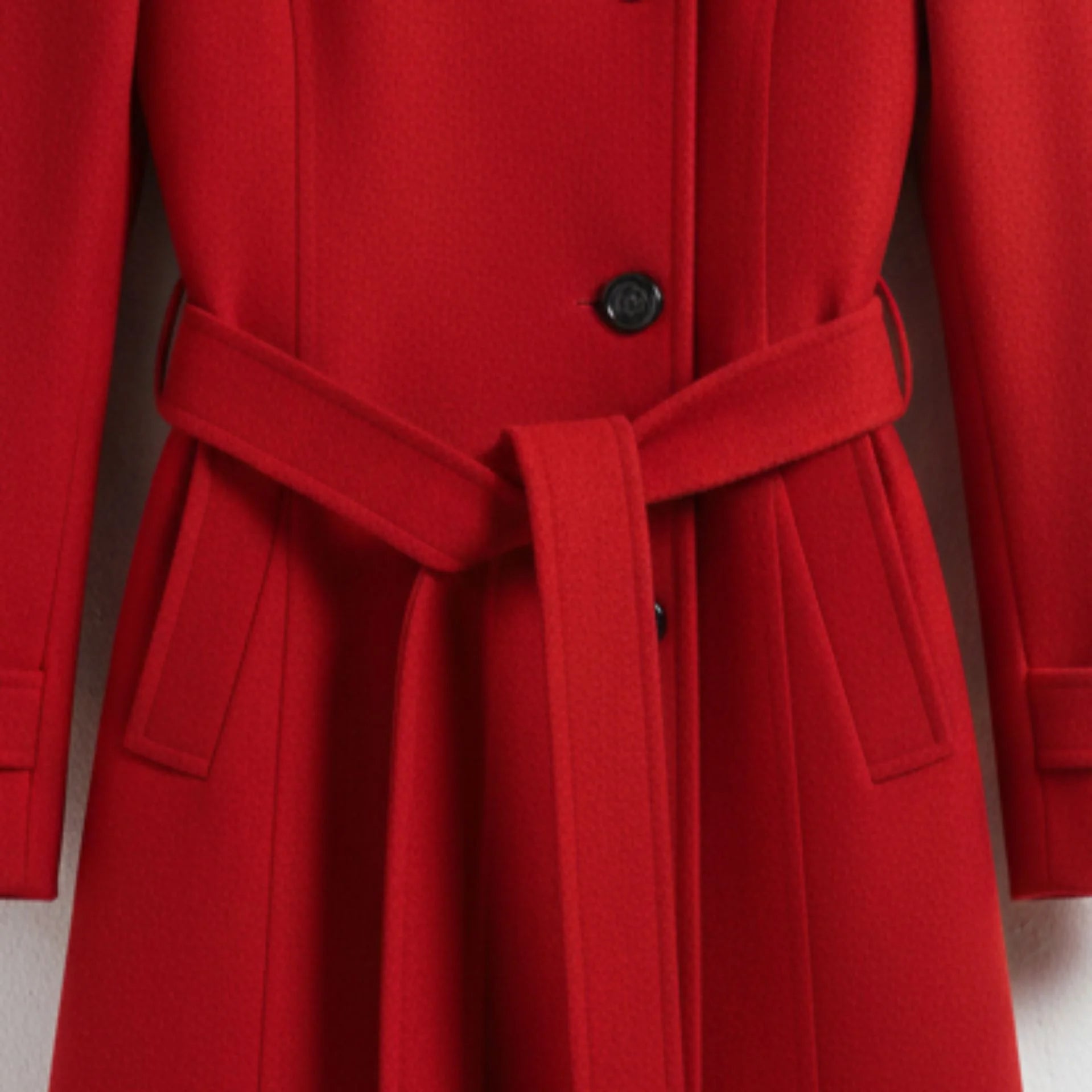 Close up of belted waist and pockets on women’s red wool dress coat