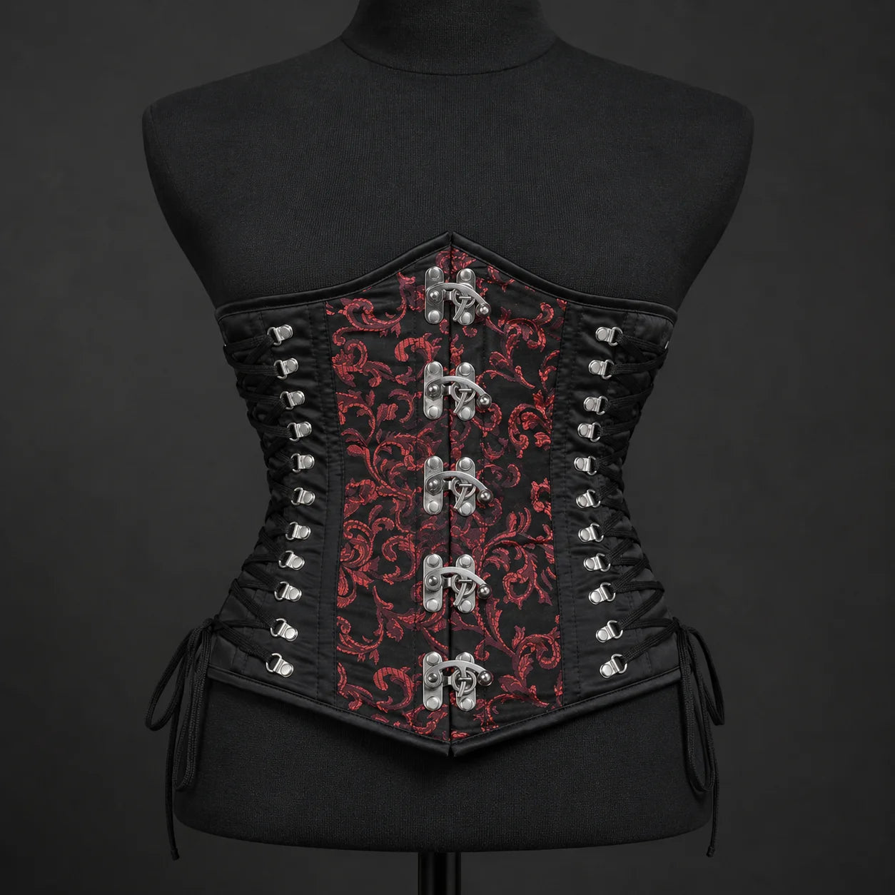 Front mannequin view of red brocade underbust corset with five metal clasps and black adjustable side lacing