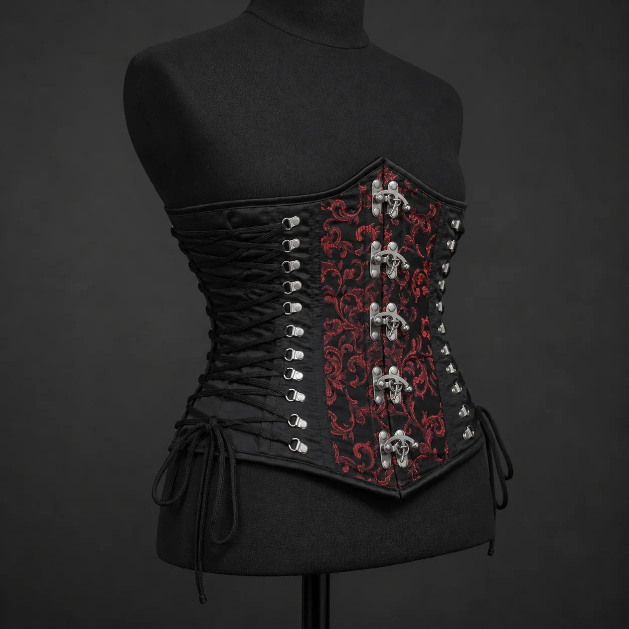 Three-quarter corset view highlighting red floral brocade centre panel, black side lacing and metal clasps