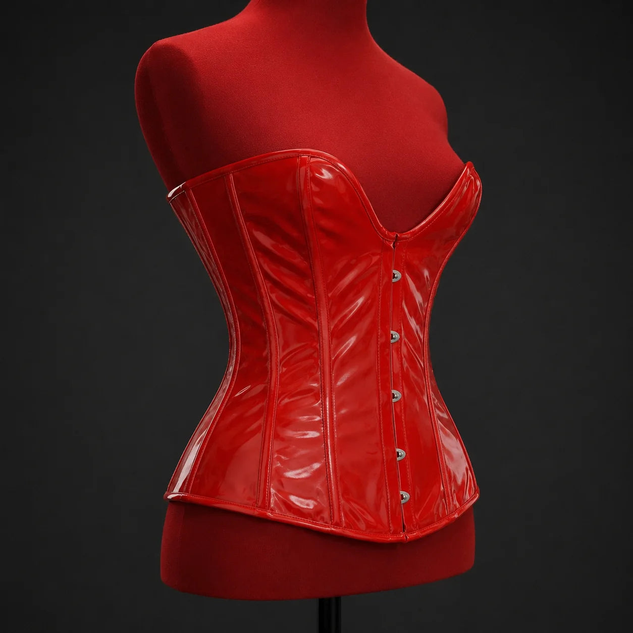Three-quarter mannequin view showing glossy red overbust corset profile, shaped waist panels and deep plunge neckline