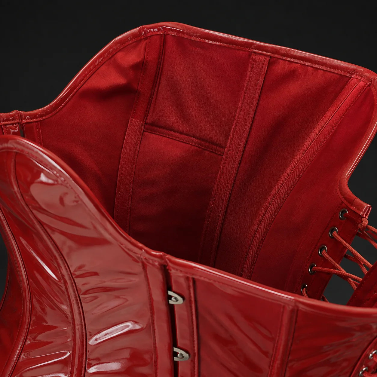 Interior close-up of red PVC overbust corset showing soft red cotton twill lining, boning channels and rear eyelet lacing