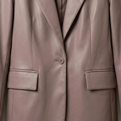 Close up of front button and flap pockets on women’s taupe leather blazer